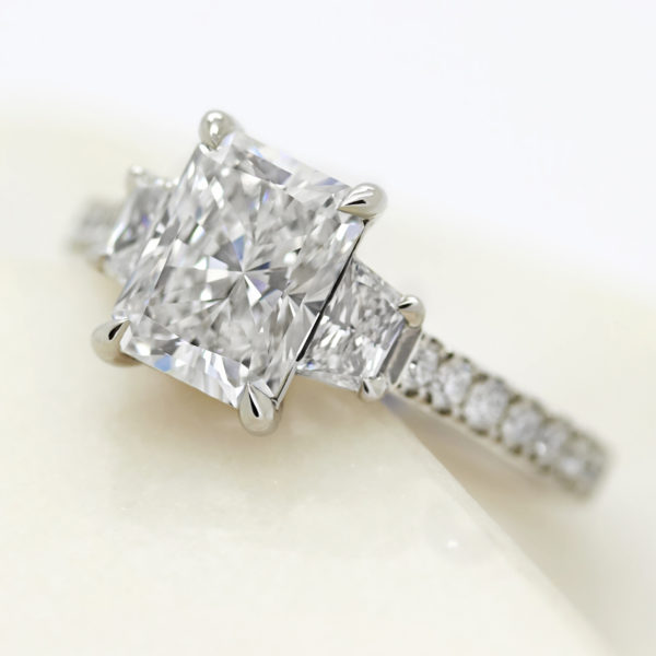 radiant cut diamond with trillion diamond side accent stones engagement ring