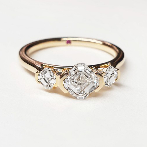 An asscher cut diamond trilogy in yellow gold