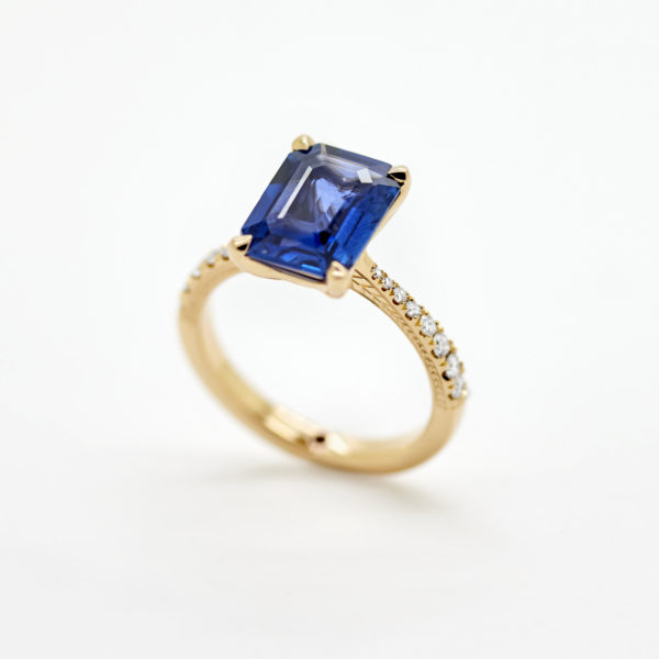 Blue sapphire emerald cut set in yellow gold with diamond pave