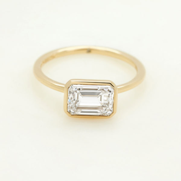 East west emerald diamond bezel set in yellow gold