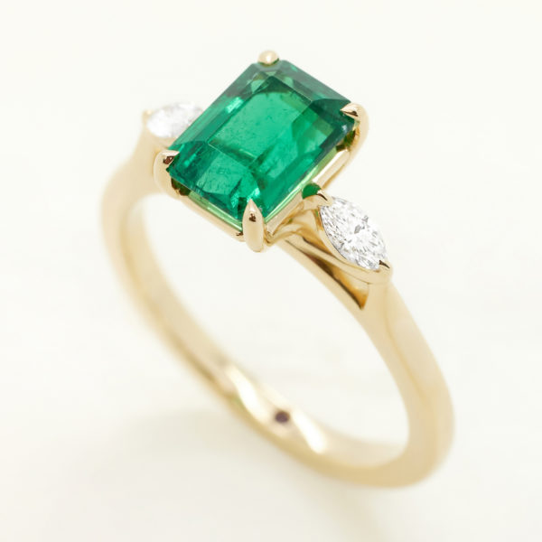 emerald cut emerald trilogy engagement ring with side pear diamonds set in yellow gold