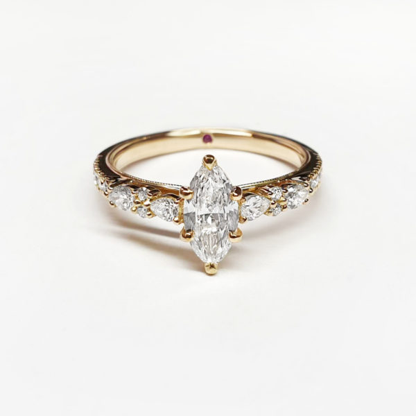Marquise diamond engagement ring set in yellow gold with a diamond band