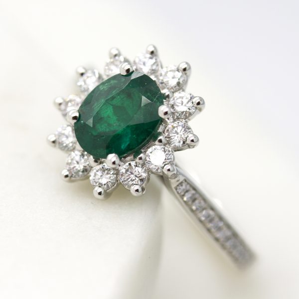 oval emerald with round diamond halo and diamond bead set engagement ring