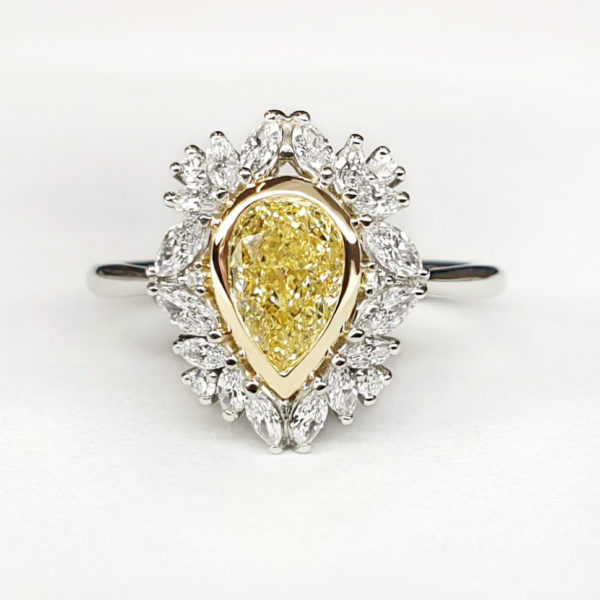 A pear shaped yellow diamond with a marquise halo