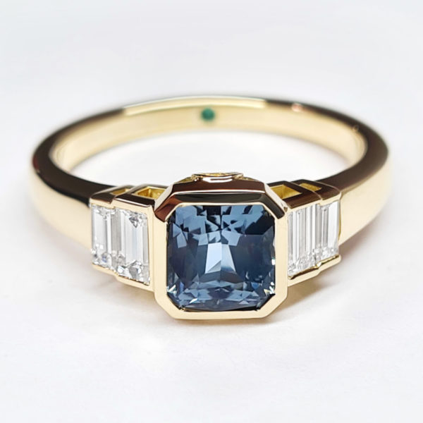 Radiant cut blue sapphire bezel set in yellow gold with baguette accent diamonds