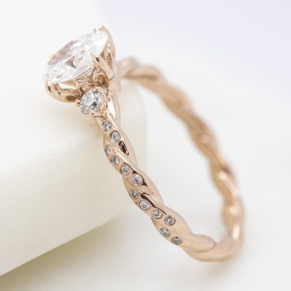 rose gold twisted engagement ring with bezel set round diamonds