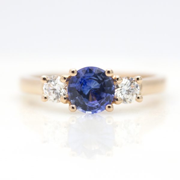 round blue sapphire trilogy engagement ring with round diamond accent stones