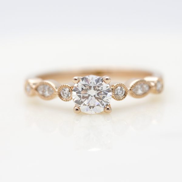 round diamond with marquise and round diamonds on the band with milgrain