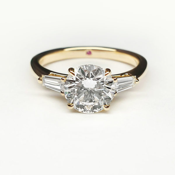 Round brilliant diamond set in yellow gold with side baguettes