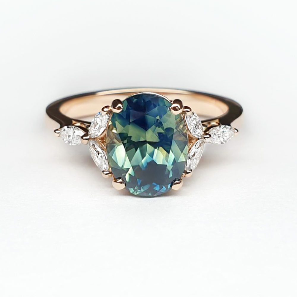 Oval shaped teal bi colour sapphire set in rose gold with marquise accent stones