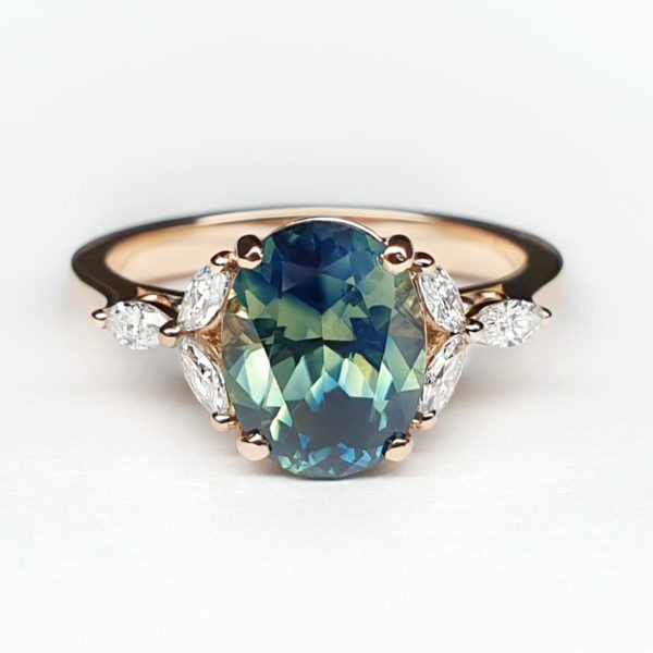 Oval shaped teal bi colour sapphire set in rose gold with marquise accent stones