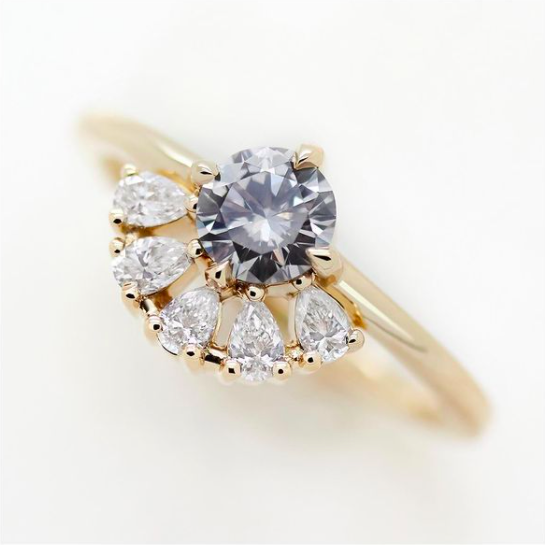 A grey diamond with pear diamond accents in yellow gold